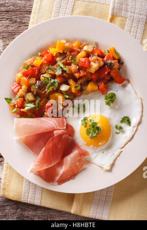 Sana colazione: uovo fritto, jamon e stufato di vegetali su una piastra di close-up. Vista verticale da sopra Foto Stock