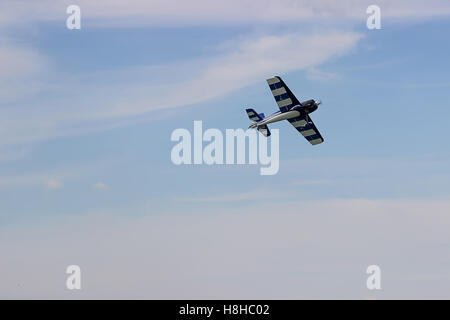 Radio Controlled aeroplano giocattolo contro il cielo blu con nuvole bianche. Modello rc aereo vola nel cielo blu. Aeroplano hobby. Foto Stock