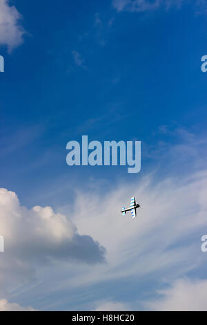 Radio Controlled aeroplano giocattolo contro il cielo blu con nuvole bianche. Modello rc aereo vola nel cielo blu. Aeroplano hobby. Foto Stock