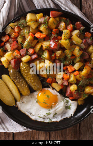 Scandinavian patate fritte con salsicce, uova e cetrioli sottaceto close-up su una piastra. vista verticale da sopra Foto Stock