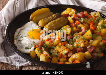 Scandinavian patate fritte con salsicce, uova e cetrioli sottaceto close-up su una piastra. Posizione orizzontale Foto Stock