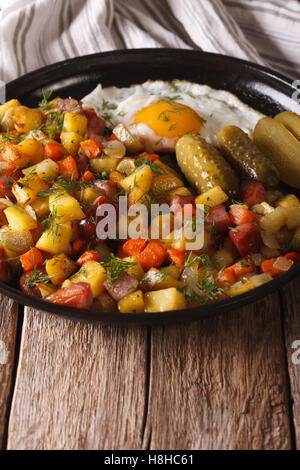 Scandinavian patate fritte con salsicce, uova e cetrioli sottaceto close-up su una piastra verticale. Foto Stock