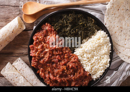 Kitfo etiope: manzo marinato con erbe aromatiche e formaggio close-up su una piastra e injera. vista orizzontale dal di sopra Foto Stock
