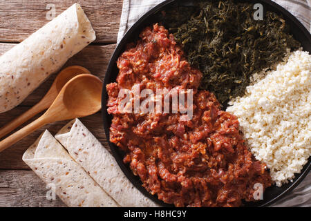 Cucina etiope: kitfo con erbe e formaggio su una piastra e injera. Vista orizzontale dal di sopra Foto Stock
