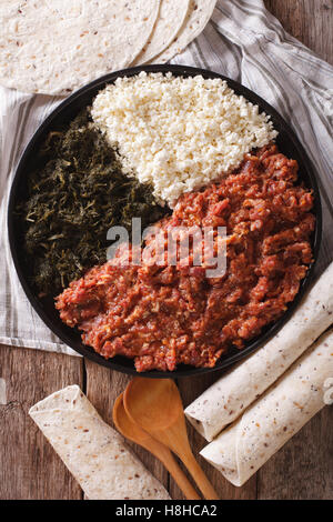 Kitfo etiope: manzo marinato con erbe aromatiche e formaggio close-up su una piastra e injera. vista verticale da sopra Foto Stock