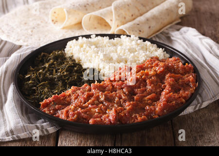 Il cibo Etiope kitfo: manzo marinato con erbe aromatiche e formaggio close-up su una piastra e injera orizzontale. Foto Stock