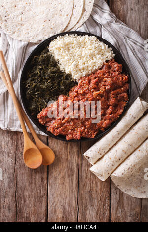 Cucina etiope: kitfo con erbe e formaggio su una piastra e injera. vista verticale da sopra Foto Stock