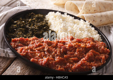 Cucina etiope: kitfo con erbe e formaggio su una piastra e injera. Posizione orizzontale Foto Stock