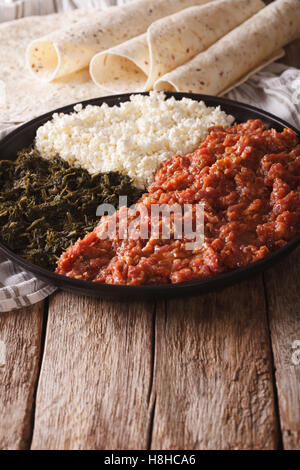 Cucina etiope: kitfo con erbe e formaggio su una piastra e injera. In verticale Foto Stock