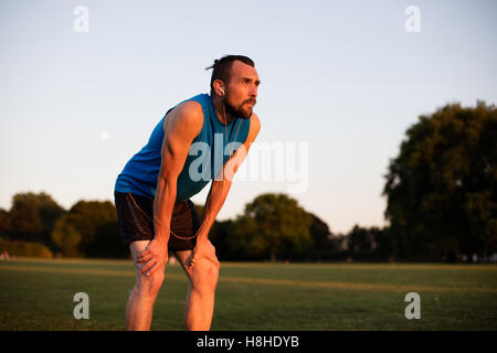 Atletica Giovane uomo riposo dopo una corsa nel parco Foto Stock