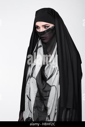 Gli occhi di bella donna che indossa la moda burka su sfondo grigio Foto Stock