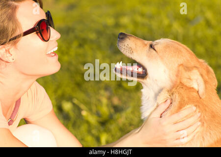 Giovane donna con un cane che giocano nel parco Foto Stock