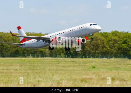 Di medie dimensioni aereo commerciale con livrea neutra tenendo fuori pista, doppio motore, fusoliera bianco, strisce rosse e motori Foto Stock