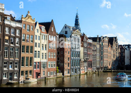 Una gita in barca lungo i motori di fronte alle famose case di rivestimento del bordo del Damrak bacino del canale, Amsterdam, Paesi Bassi Foto Stock