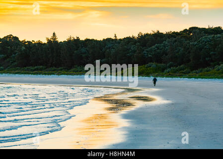 Una persona solitaria passeggiate lungo una spiaggia Foto Stock