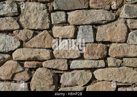 Sezione di muro di pietra con pietre perfettamente interbloccanti e pietre irregolari. Per il settore edile del Regno Unito. Foto Stock