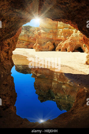 Vista di sunshiny spiaggia sabbiosa attraverso arco roccioso (Dos Tres Irmaos, Portimao Alvor, Algarve, Portogallo). Foto Stock