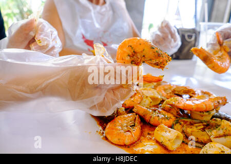 Pesce crostacei Mitili, ostriche e gamberetti con la mano sul tavolo e cera bianca carta, il fuoco selettivo cibo sfondo. Foto Stock