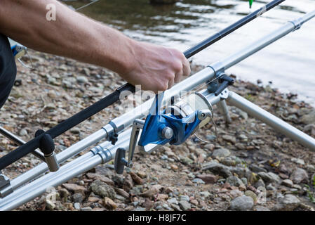 Le avventure di pesca - Primo piano di una mano che afferra una canna da pesca con mulinello Foto Stock