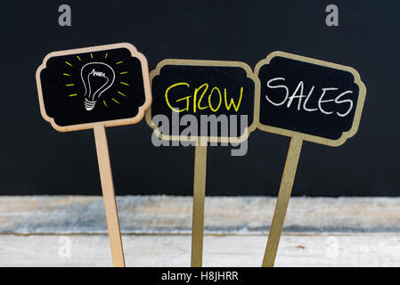 Messaggio di concetto di aumentare le vendite e la lampadina della luce come simbolo per idea scritto con un gessetto su legno mini etichette di Blackboard Foto Stock