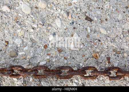 Grande metallo arrugginito catena sul muro di pietra Foto Stock