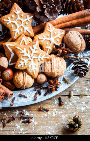 Decorazioni di Natale con fatti in casa gingerbread cookies stelle, coni, i dadi e le spezie di Natale su rustico sfondo di legno Foto Stock