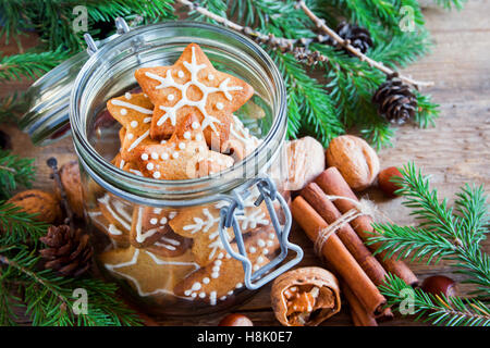 Lo zenzero biscotti di Natale stelle nel vasetto di vetro con rami di abete e decorazioni di Natale close up Foto Stock