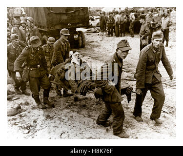 PRIGIONIERI FERITI NAZISTI D-Day operazione Overlord WW2 POW tedeschi trasportano compagni feriti a bordo di un'imbarcazione di atterraggio su una spiaggia di Normandia con truppe americane dietro June1944 nord della Francia Foto Stock