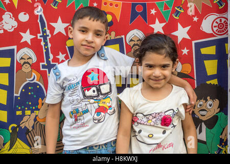 Il Cairo, Egitto. Egiziano giovane ragazzo e ragazza in piedi insieme nella parte anteriore di un colorato sfondo cartoon nel bazaar all'aperto/ flea Foto Stock