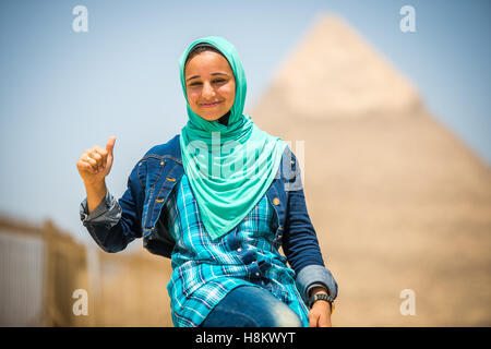 Il Cairo, Egitto donna egiziana seduti di fronte le Grandi Piramidi di Giza che sono in background. Questo particolare è Th Foto Stock