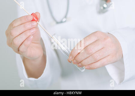 Femmina specialista medico tenendo buccale un batuffolo di cotone e il tubo di prova, pronto a raccogliere il DNA Foto Stock