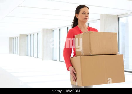 Metà adulto imprenditrice che trasportano le scatole di cartone nel nuovo ufficio Foto Stock