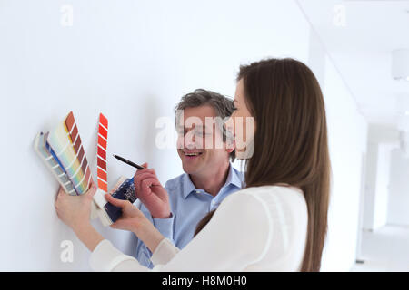 Sorridente la gente di affari la scelta dei campioni di colore contro la parete in ufficio Foto Stock