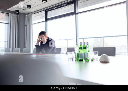 Imprenditore maturo che soffrono di mal di testa al tavolo da conferenza Foto Stock