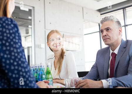 Sorridente giovane imprenditrice con i colleghi in sala riunioni Foto Stock