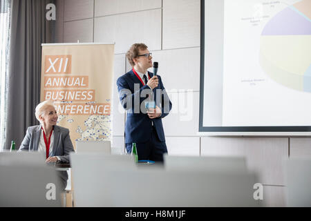 Imprenditore spiegando il grafico a torta in seminario hall di convention center Foto Stock