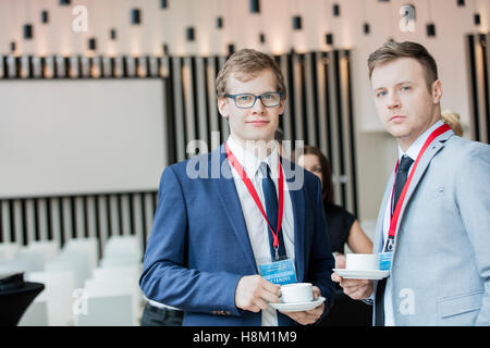 Ritratto di certi imprenditori azienda tazze da caffè in convention center Foto Stock