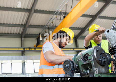 Basso angolo di visione dei lavoratori manuali lavora su macchinari nel settore metalmeccanico Foto Stock