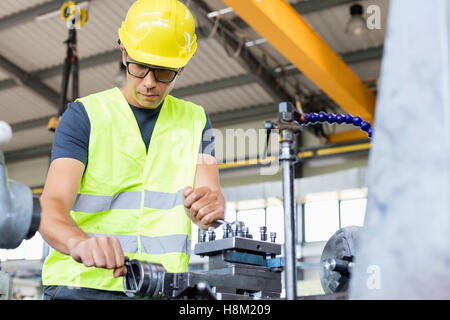 Basso angolo vista di metà adulto lavoratore macchinari operativi nell industria del metallo Foto Stock