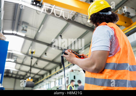 Basso angolo vista del giovane lavoratore manuale Gru operativa in fabbrica Foto Stock