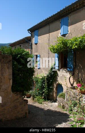 Tipica pietra costruita casa rurale in Francia con la sua persiane blu e arco porta in una zona molto freccia street Foto Stock