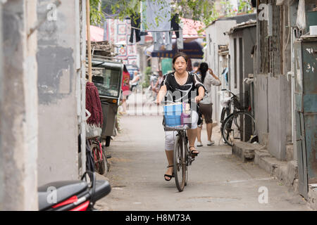 Pechino, Cina - la Giovane donna cavalcare il suo moto in un hutong situato nel centro di Pechino. Foto Stock