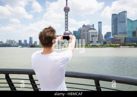 Vista posteriore dell'uomo fotografare la Oriental Pearl Tower mentre in piedi dalla ringhiera Foto Stock