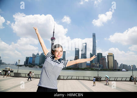 Ritratto di donna felice in piedi con le braccia distese sul lungomare contro lo skyline di Pudong Foto Stock