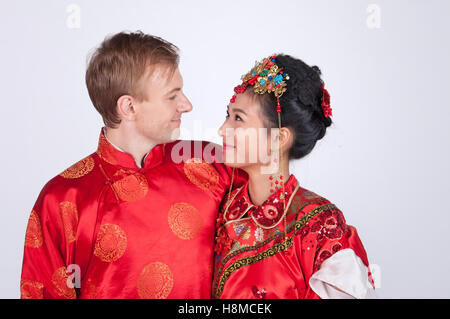 Razza mista sposa e lo sposo in Studio indossando il tradizionale cinese corredi nuziali Foto Stock