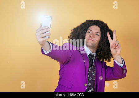 Uomo caucasico con Afro indossa vestito viola prendendo un selfie Foto Stock