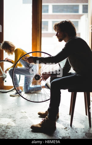 Mechanic esame di una ruota di bicicletta Foto Stock