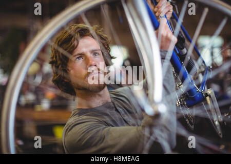 Mechanic esame di una ruota di bicicletta Foto Stock