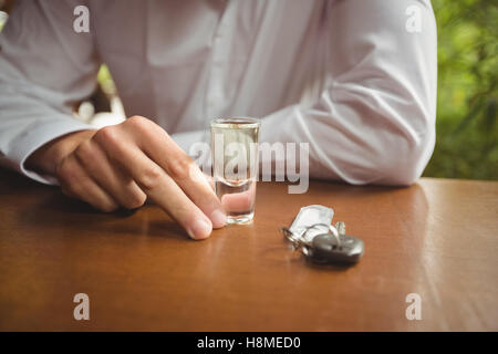 Uomo con un bicchiere di tequila shot nel bancone bar Foto Stock