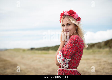 Donna bionda che indossa un fiore tiara in piedi in campo Foto Stock